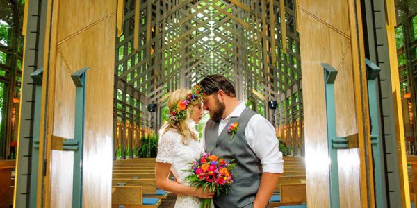 Couple Standing Outside of Chapel Holding Flowers